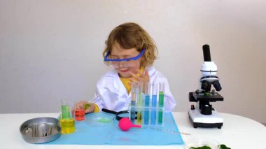 Test tüpleri, reaktörleri ve mikroskobu olan bir çocuğun laboratuvar incelemesi. Seçici odaklanma. çocuk.