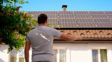 Adam evin çatısındaki güneş panellerine bakıyor. Seçici odaklanma. insanlar.