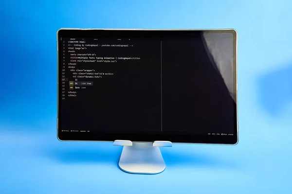 Writing computer code displayed on monitor light blue background