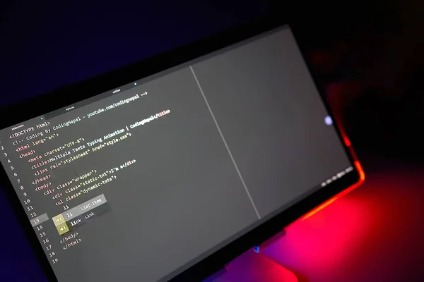 Writing computer code displayed on monitor neon red back light