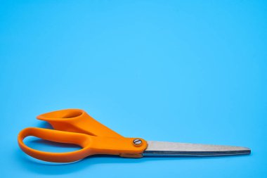 Orange shear scissors on a light blue background cutting shears baby blue