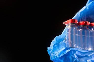 Medical gloves and vials on black background for needle injection containers