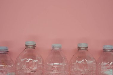 Empty plastic water bottles recycle material reduce waste light pink background