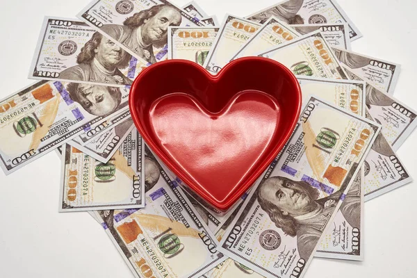 for the love of money heart shape one hundred dollar bills on white background red bowl