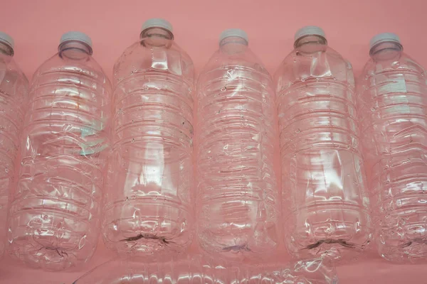 Empty plastic water bottles recycle material reduce waste light pink background