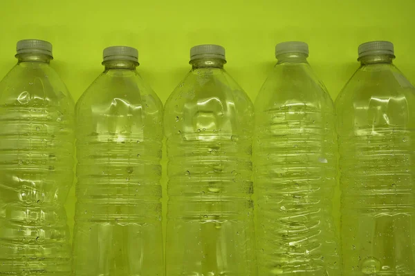 Empty plastic water bottles recycle material reduce waste neon green background