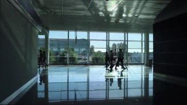 Münih uluslararası havaalanındaki 2 numaralı terminalin kapısında yürüyen yolcuların siluetleri.