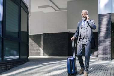 Bavuluyla akıllı telefondan konuşan kendinden emin yaşlı bir girişimci. Şehirdeki ofis binasının önünden geçen son sınıf erkek takım elbiseli bir adam. Güneşli bir günde dizüstü bilgisayar çantası taşıyor..