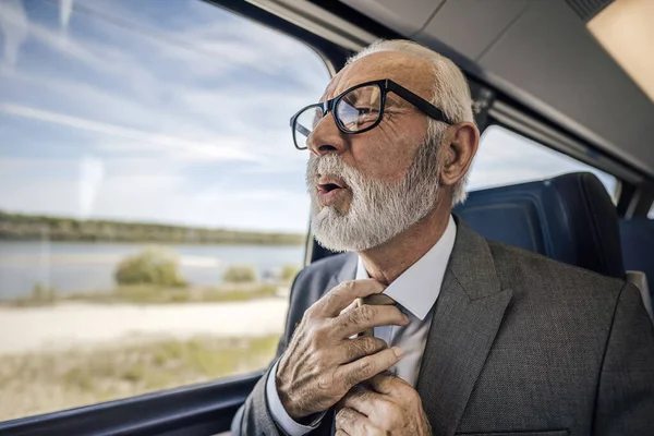 Close-up of stressed senior businessman feeling uncomfortable while traveling on the train having a heart attack.