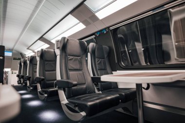 Tren vagonunda pencere kenarındaki masa ve rahat deri koltuklar. Modern yolcu treninin içi. Demiryolu taşıma kipi.