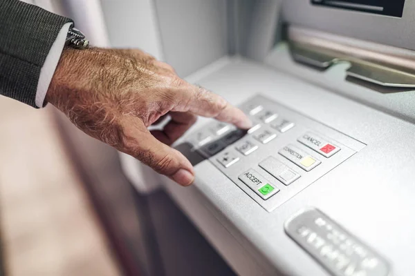 stock image Close-up of senior male professional entering PIN in ATM machine. Cropped image of businessman pushing buttons on keypad. He is withdrawing money by using electronic banking.