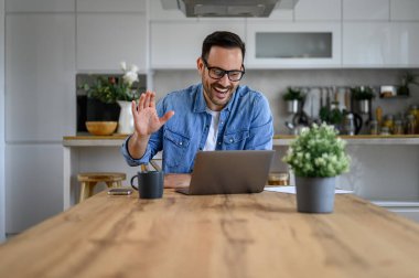Keyifli genç işadamı el sallarken video ofisteki bilgisayarı arıyor.