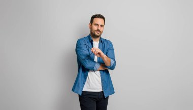 Gözlük tutan ve gri arka planda ciddi poz veren kendine güvenen çekici iş adamının portresi.