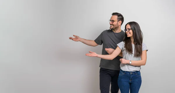 微笑的年轻男友和女朋友展示广告的复制空间 幸福的夫妻戴着眼镜和便宜货 在背景下展示空旷的行销空间 — 图库照片