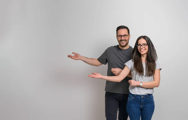 欢乐的男女青年在广告的复制空间上做手势的画像 笑的夫妻戴着眼镜 代表空余的晋升空间 — 图库照片