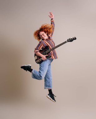 Neşeli bayan müzisyen gitarla havalarda zıplıyor arka planda