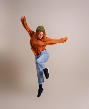 Heyecanlı, başarılı, kollarını açmış arka planda havaya zıplayan genç bir kadın.