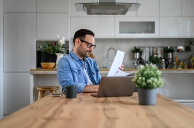 Bilgisayarlı genç girişimci, merkez ofisten çalışırken mali raporları analiz ediyor.