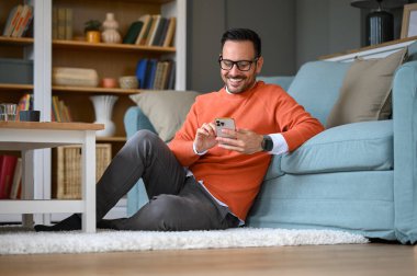 Ofisteki koltukta otururken sosyal medyayı cep telefonundan kontrol eden kendine güvenen bir işadamı.