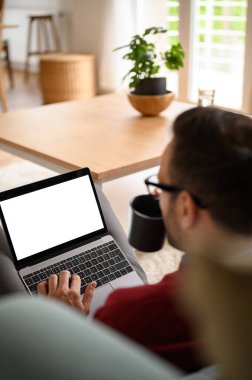 İş adamının kahve içmesi ve ev ofisinde otururken dizüstü bilgisayarla çalışması.