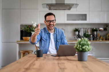 Ofisteki laptopun üzerinde çalışırken, yakışıklı iş adamı işaret veriyor.