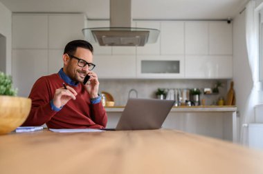 İç işlerinde çalışırken elinde kalem tutan ve cep telefonuyla tartışan yakışıklı bir serbest yazar.