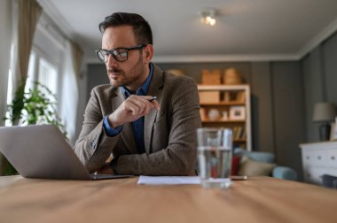 Evde çalışırken bilgisayardan e-posta okuyan zarif erkek girişimcinin düşük açılı görüntüsü