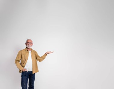 Kendine güvenen üst düzey erkek, yeni ürünü sunuyor ve beyaz arka planda kameraya gülümsüyor.