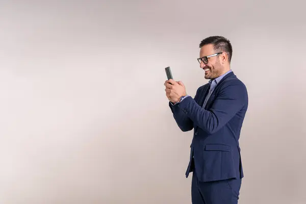 Smiling young businessman doing social media marketing over mobile phone against white background