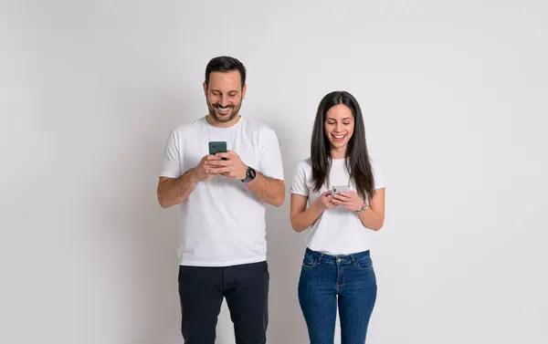 Alegre Pareja Joven Sonriendo Desplazando Aplicaciones Redes Sociales Teléfonos Inteligentes — Foto de Stock