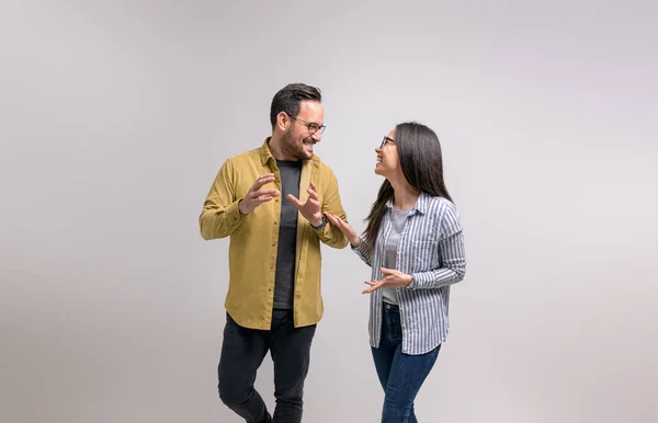 Ecstatic young partners laughing and discussing new project while standing against white background