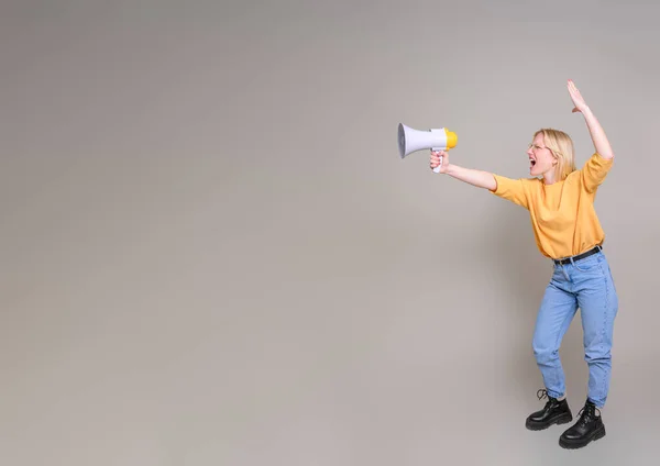 Full length of female speaker with arm raised shouting over megaphone on isolated white background