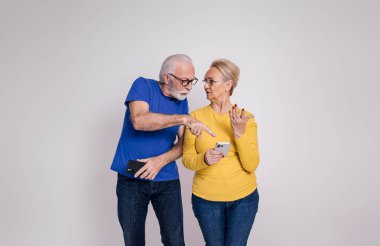 Şüpheli kıdemli koca, beyaz arka planda eşinin akıllı telefonundaki mesajlara işaret ediyor.