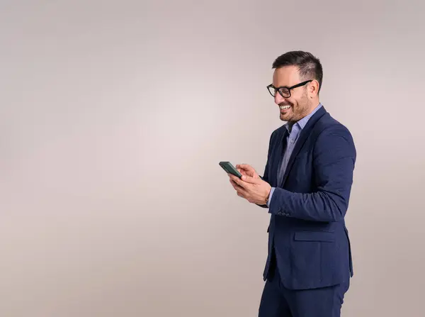 Smiling young businessman doing social media marketing over smart phone against white background