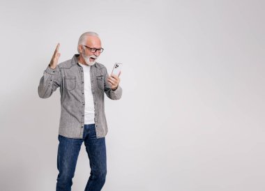 Beyaz arka planda akıllı telefondan iyi haberler okuduktan sonra çığlık atan kendinden geçmiş yaşlı bir girişimci.