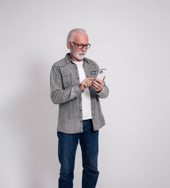 İzole edilmiş beyaz arka planda cep telefonuyla mesajlaşan kendinden emin yaşlı erkek yöneticinin portresi