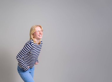 Elleri ceplerinde gülümseyen kadın girişimci beyaz arka plana neşeyle bakıyor.