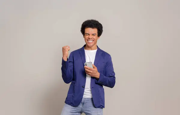 Возбужденный Молодой Человек Афроволосами Держащий Смартфон Играющий Гитаре Белом Фоне — стоковое фото
