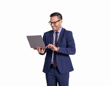 Gözlüklü genç işadamının portresi gülümsüyor ve beyaz arka planda dizüstü bilgisayarla çalışıyor.