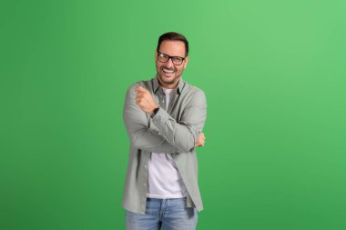 Genç yakışıklı profesyonel portresi kameraya gülümsüyor ve yeşil arka planda poz veriyor.
