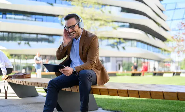 Üzletember Fejhallgatóban Videohívás Közben Touchpad Miközben Padon Városban Stock Kép