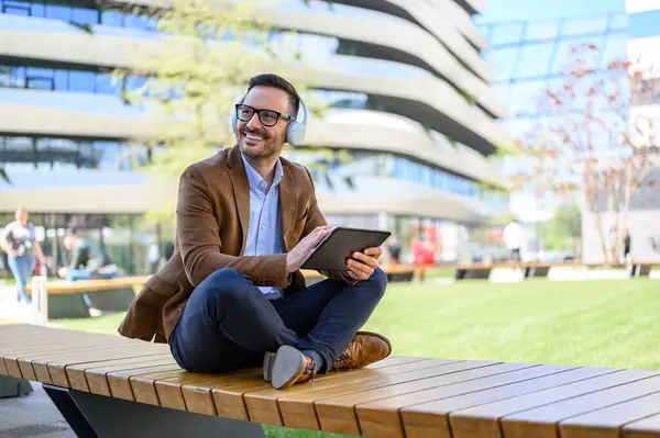 Smiling Professional Headphones Digital Tablet Looking Away Sitting Bench City Ліцензійні Стокові Фото