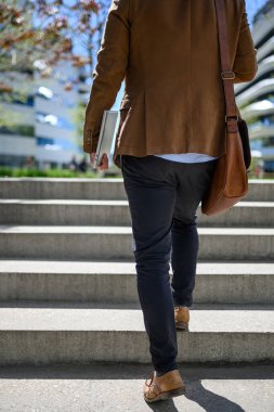 İş adamlarının omuz çantalı ve dizüstü bilgisayarlı alt kesimi basamakları tırmanıyor ve şehirde iş çıkışı yapıyor.