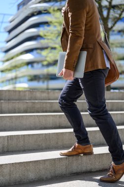 Genç işadamlarının dizüstü bilgisayarı tuttukları ve güneşli bir günde şehirde merdivenlerde yürüdükleri yer.