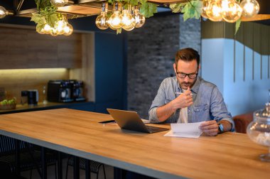 Aydınlanmış ofiste masa başında çalışırken ciddi mali danışman okuma ve denetleme raporu