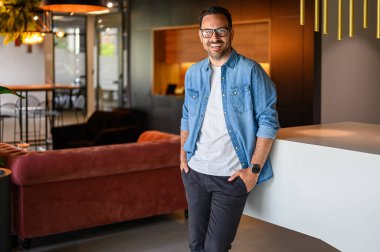 Modern ofiste duran, elleri ve gözlüklü, kendinden emin finansal danışmanın portresi.