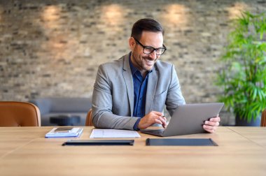 Gözlüklü yakışıklı bilişim mühendisi gülümseyen ve geliştiren bir web sitesi modern ofiste masanın üzerinde.