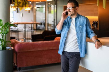 Ofiste dururken telefonla iletişim kuran gözlüklü gülümseyen bir satıcının portresi.