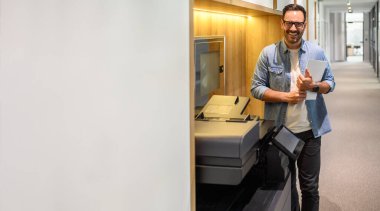 Kontrat belgelerini tutan gözlüklü erkek yazıcının portresi ve koridorda fotokopi makinesi duruyor.