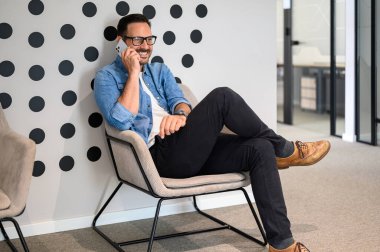 Tam boy erkek mühendis koltukta otururken telefonda gülümsüyor ve tartışıyorlar.